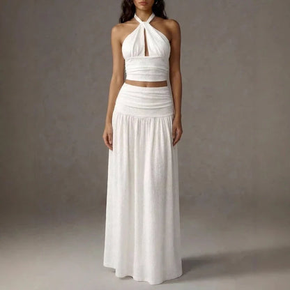 White two-piece set featuring a halter crop top with a keyhole cut and a matching pleated maxi skirt.