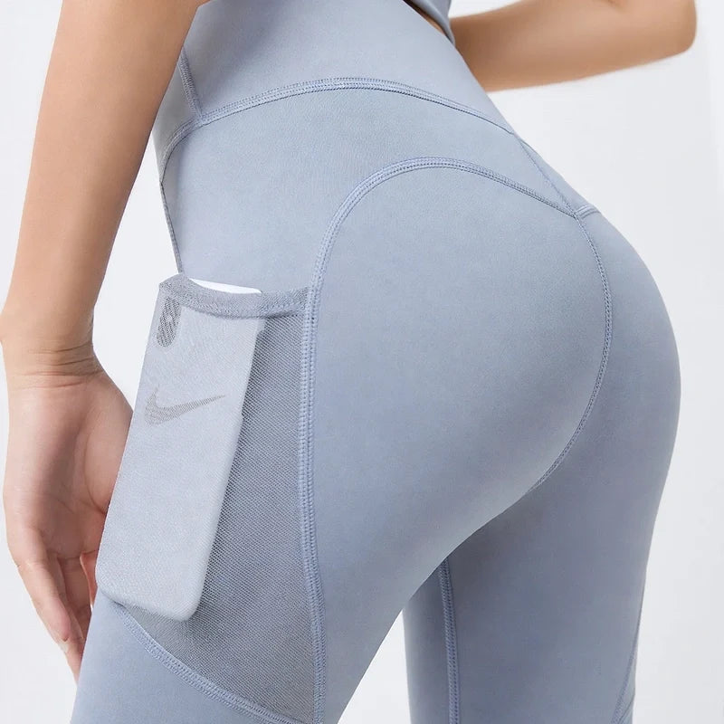 Side view of light blue yoga leggings featuring a mesh side pocket holding a smartphone.