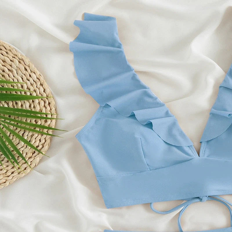 Light blue bikini top with ruffled straps and a deep V-neck on a white background.