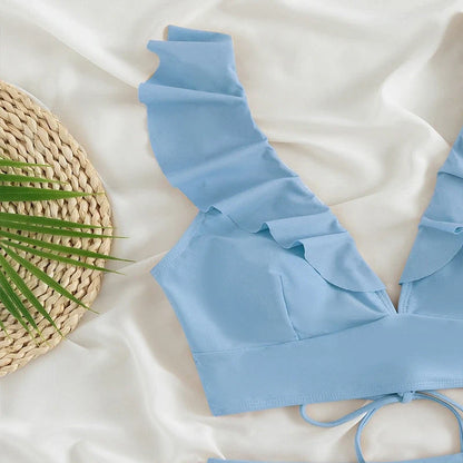 Light blue bikini top with ruffled straps and a deep V-neck on a white background.