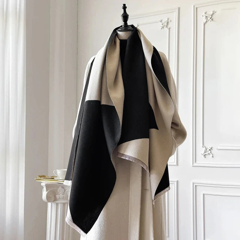Black and beige color-blocked knit shawl wrap with fringe on a dress form