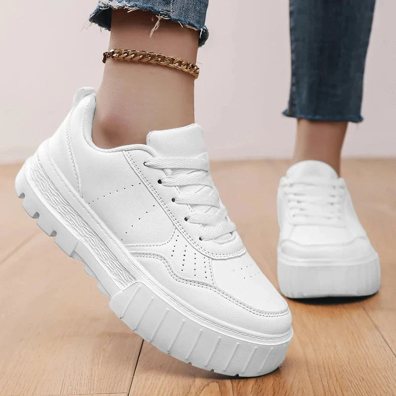 Close-up of white platform sneakers with a chunky lug sole worn on a person with cuffed jeans.