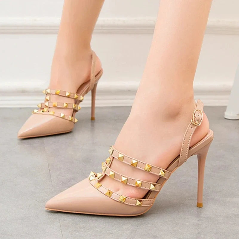 Beige patent leather slingback stiletto pumps with pointed toes and three studded straps.