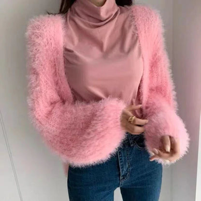 Pink fuzzy cropped jacket with balloon sleeves worn over a pink turtleneck and blue jeans