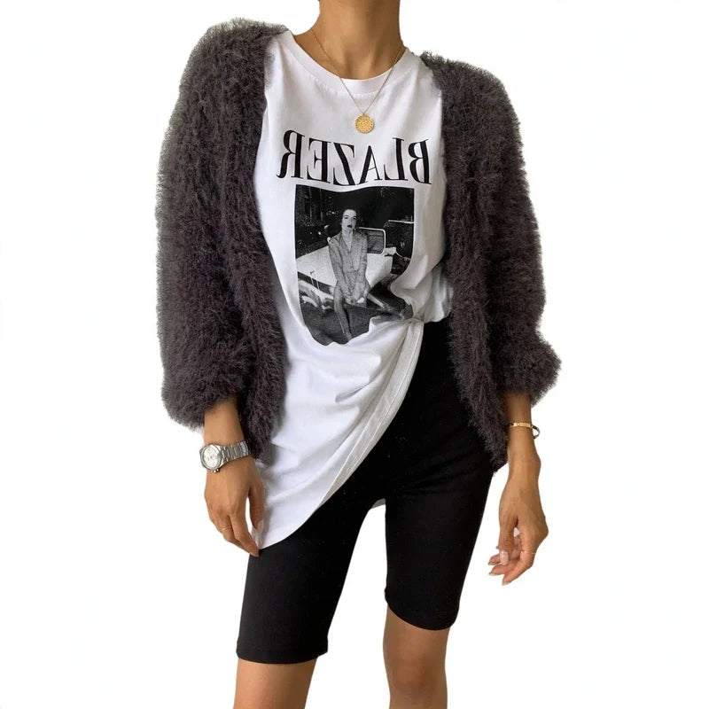 Woman wearing a charcoal fuzzy cardigan over a graphic t-shirt and black shorts.
