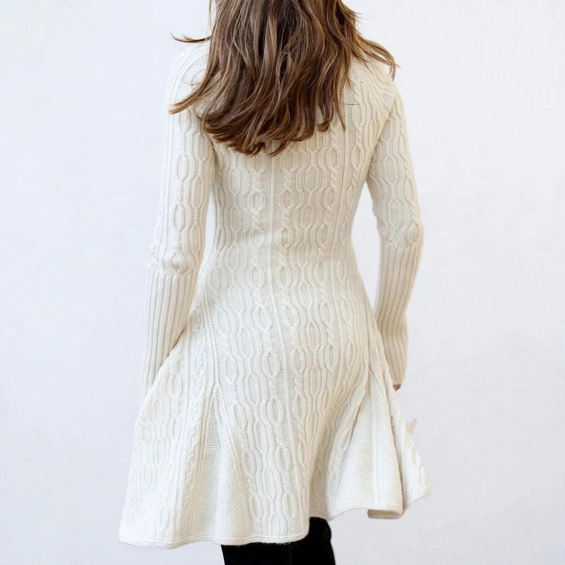 Rear view of a cream cable knit sweater dress with long sleeves and a flared hem.