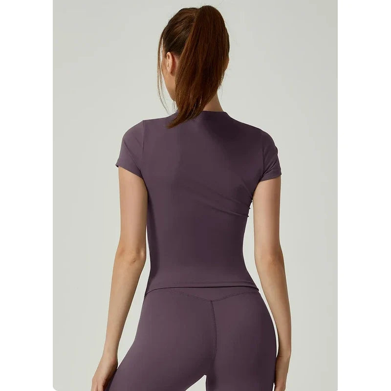 Back view of a woman wearing a short-sleeve workout top in dark purple.