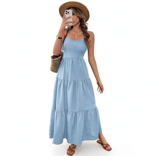Woman wearing a light blue tiered maxi dress with a straw hat and sandals, taking a mirror selfie.