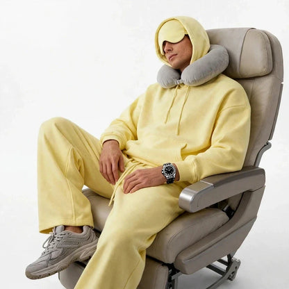 Men's pale yellow fleece travel hoodie with built in eye mask worn in an airplane seat