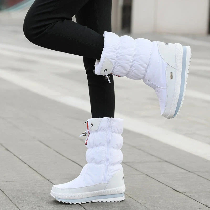 White quilted mid-calf winter boots with side zippers and chunky platform soles worn with black leggings.