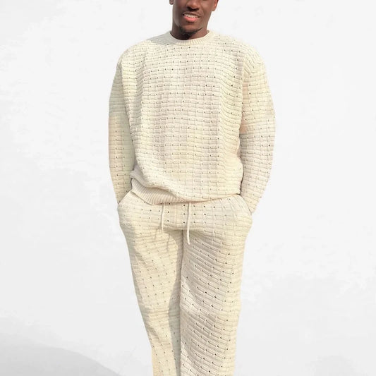 Man wearing a cream knit crewneck sweater and matching drawstring pants set.
