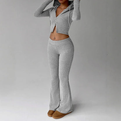 Model wearing a grey ribbed knit zip-up crop hoodie and matching flared pants with brown slip-on shoes.